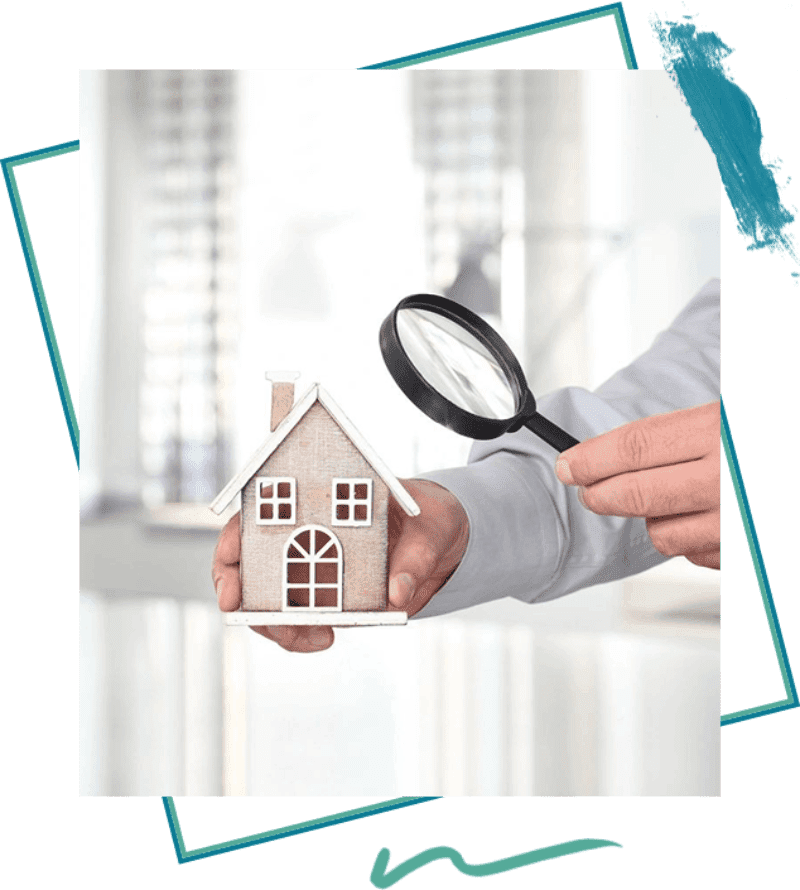 A person holding a small house and magnifying glass