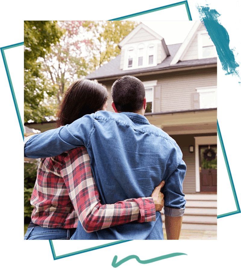 A man and woman hugging in front of a house.